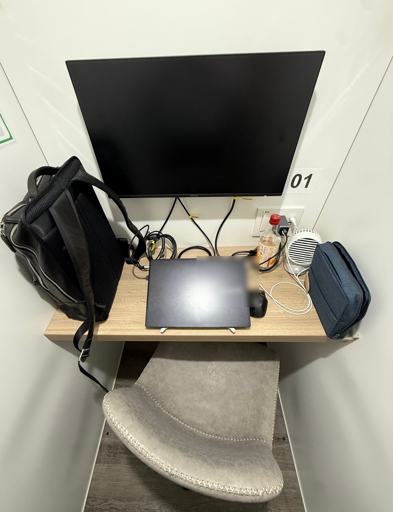 SoloWork中野北口のブース内。23.8型モニターの下の机（横100cm・奥行45cm）にノートPC・マウス・ポーチ・500mlペットボトルを置いた状態